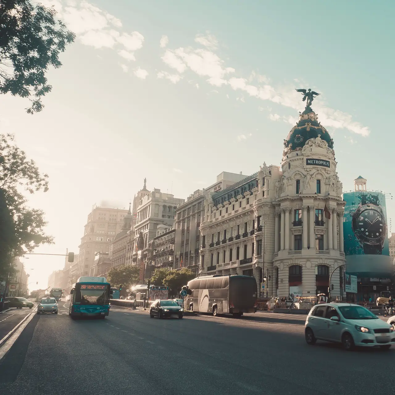El edificio Metrópolis visto desde la calle de Alcalá una mañana de sol, con un coche blanco y un autobús por la calzada